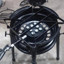 Fogão industrial a gás preto com base metálica e queimador circular em chão de cimento