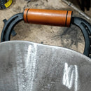 Alça de madeira e metal de ferramenta agrícola com superfícies desgastadas em fundo de chão de oficina