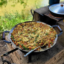 Arroz temperado com legumes, queijo e ervas em panela grande ao ar livre